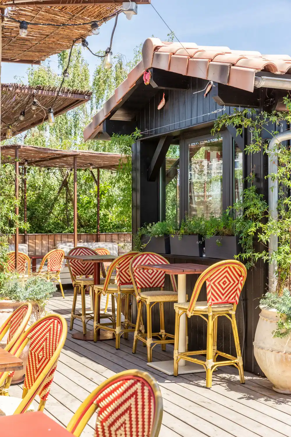 Terrasse extérieure avec de jolies chaises rouges et avec beaucoup de verdure pour ce restaurant à Toulouse.